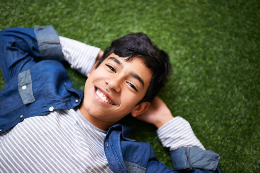 Its awesome being a kid. A young boy relaxing on the lawn.