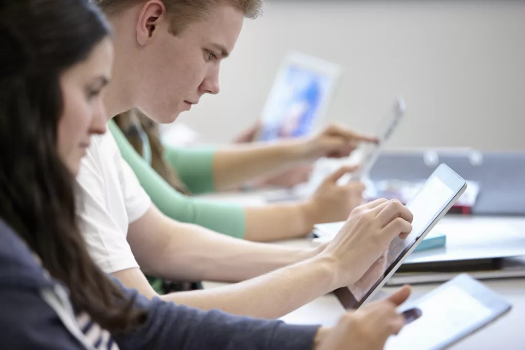 Teenagers using digital tablets classroom