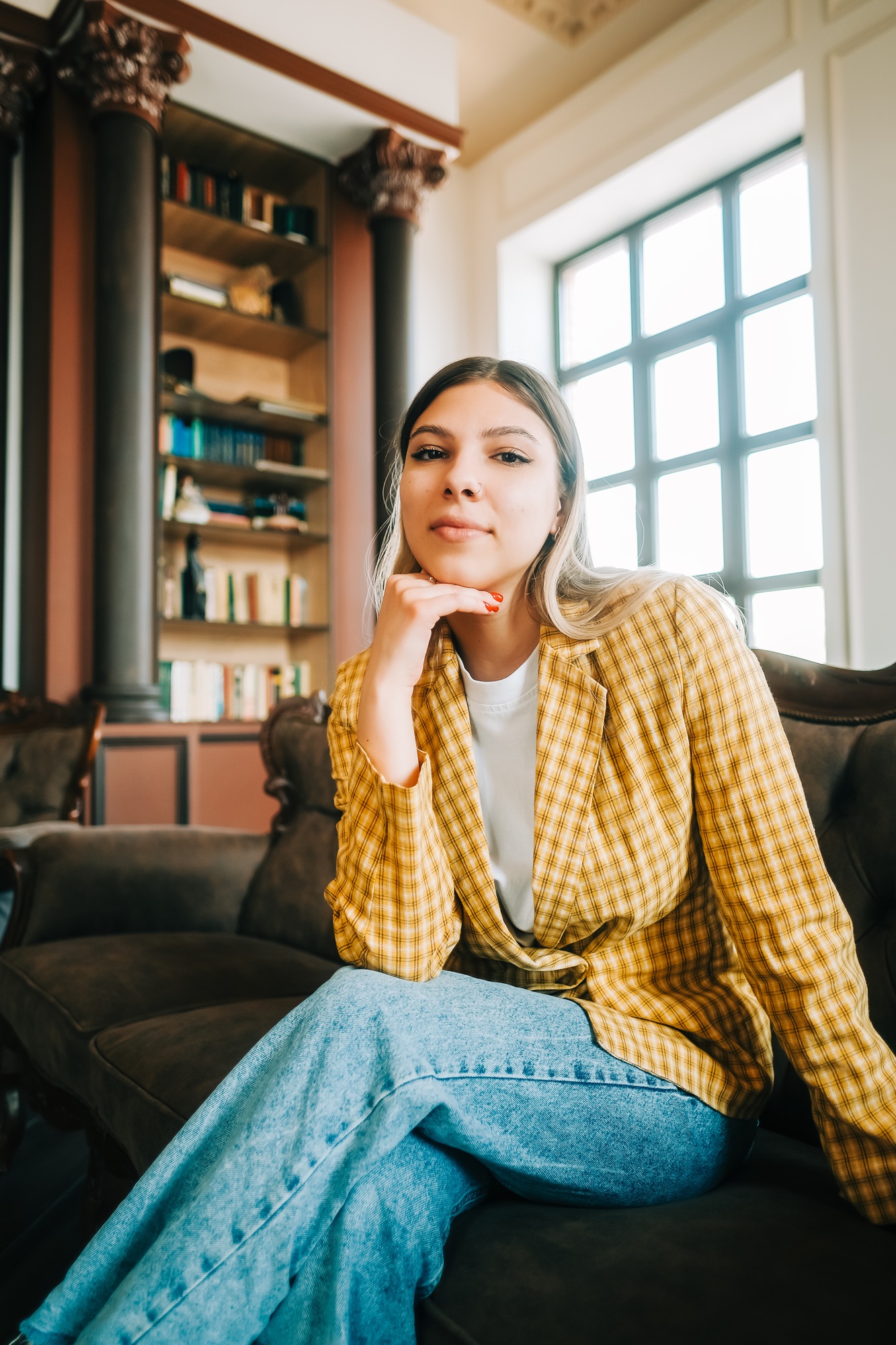Portrait of attractive confident business woman in business suit siting on a sofa in a hall.